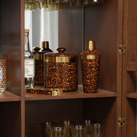 Leopard print barware set on a wooden shelf with a glass cabinet in the background.