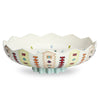 A decorative ceramic bowl with a scalloped rim and pedestal base, decorated with colorful geometric patterns in red, yellow, blue, and green on an off-white background.