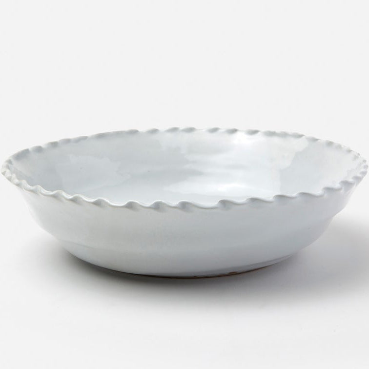 A shallow round ceramic bowl with a scalloped, wavy rim, shown on a clean white background.