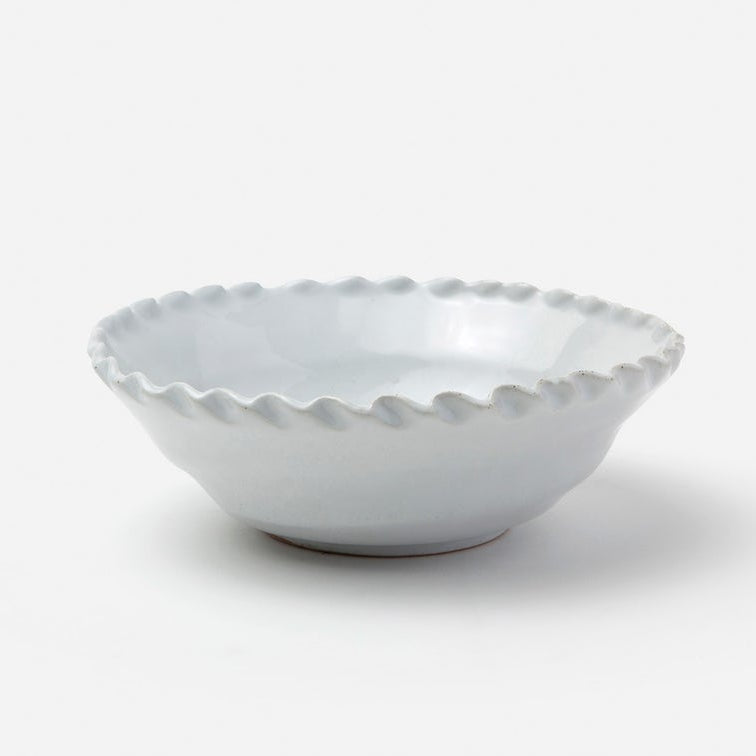 A small white ceramic bowl with a scalloped rim, photographed on a clean white background.