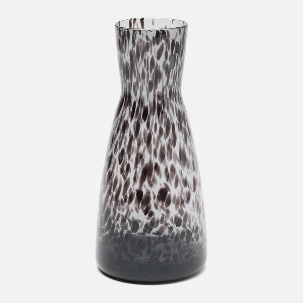 A tall, flared glass carafe with a dark brown and white leopard-like spotted pattern, shown against a plain light gray background.