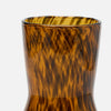 Close-up of a textured amber glass vase with a wavy, flame-like pattern on a light gray background.