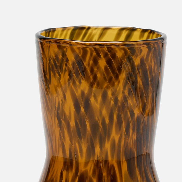 Close-up of a textured amber glass vase with a wavy, flame-like pattern on a light gray background.