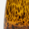 Close-up of a glossy amber glass object with a dark brown mottled or leopard-like pattern, photographed against a plain white background.
