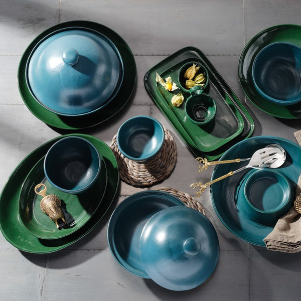 Collection of green and blue ceramic dishes and tableware on a light gray surface.