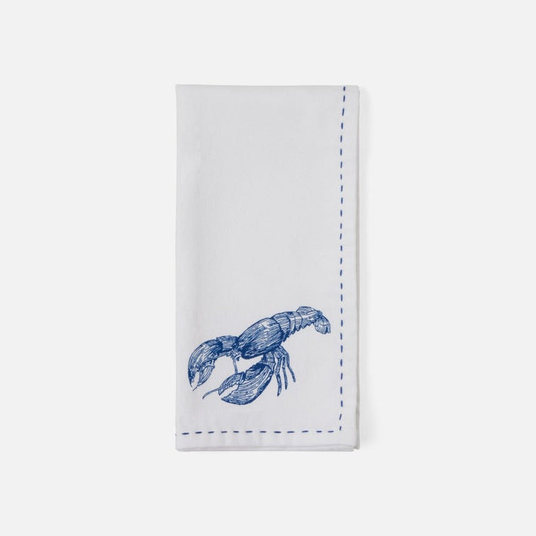A white napkin with a blue lobster illustration and blue dashed border stitching, shown flat against a light gray background.