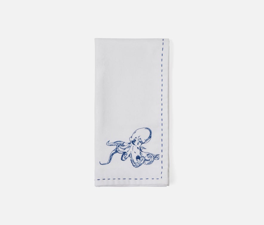 A white rectangular fabric napkin with blue stitched borders and a blue octopus illustration near the bottom, shown on a light gray background.