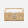 Woven rectangular napkin basket with a white interior on a light beige background