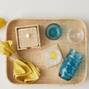 Tray with coaster box, star-shaped items, and blue glassware on a light background