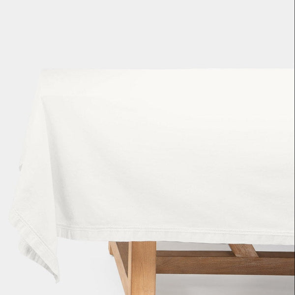 A white tablecloth draped over a wooden table, shown against a plain white background.
