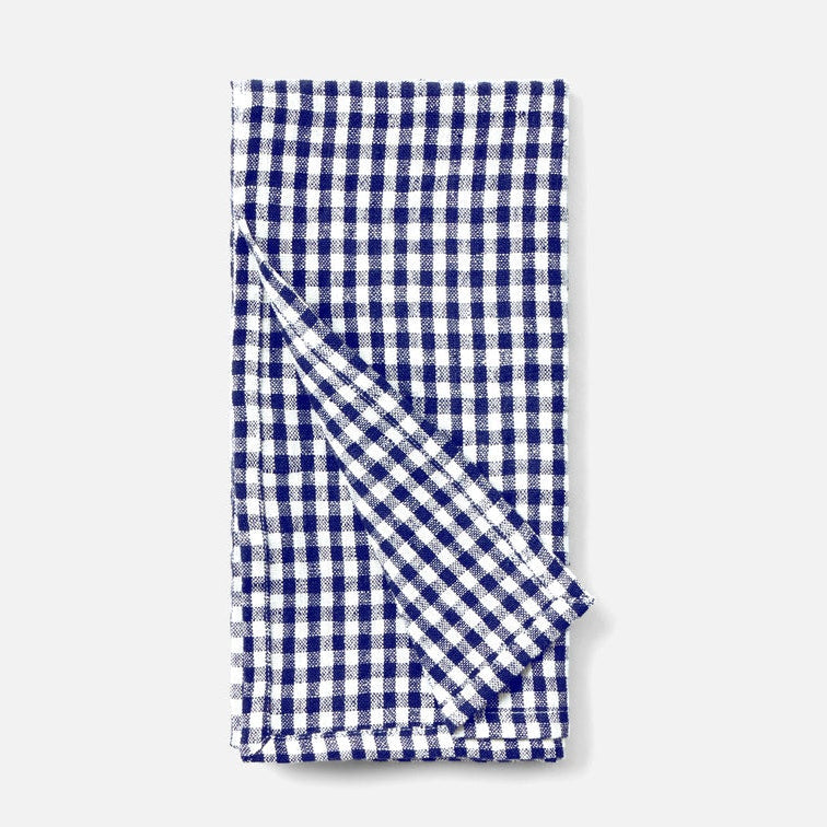 A folded cotton kitchen napkin with a classic navy blue and white gingham checkered pattern, shown on a clean light gray background.