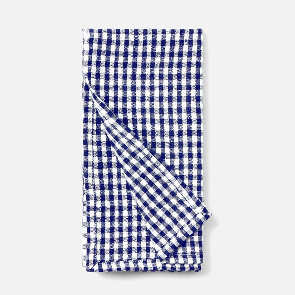 A folded cotton kitchen napkin with a classic navy blue and white gingham checkered pattern, shown on a clean light gray background.