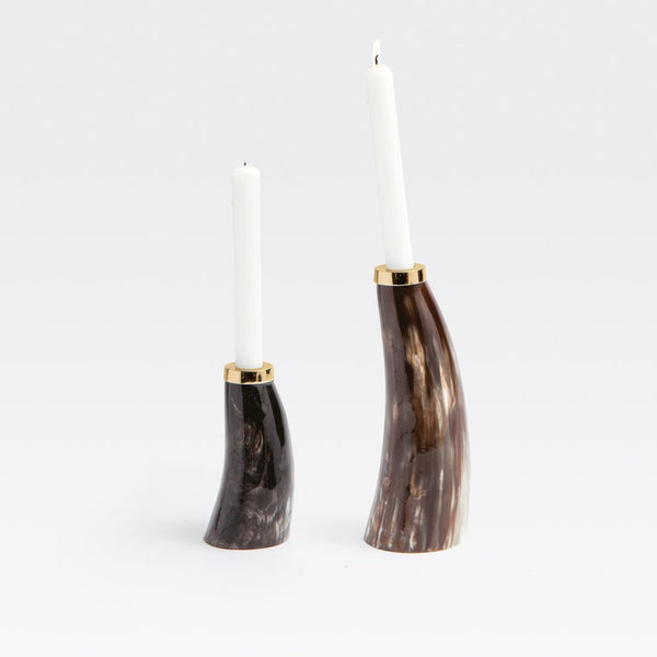 Two curved candle holders made of dark brown and black marbled horn, each holding a white taper candle, photographed on a clean white background.