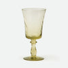 A single translucent pale green glass goblet with a twisted stem design, standing on a light gray background.