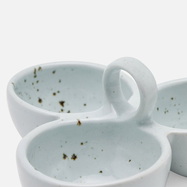 Stoneware snack dish with integrated loop handles, shown in a close-up studio shot on a white background. The dish has a pale icy blue-green glaze with scattered dark speckles inside.