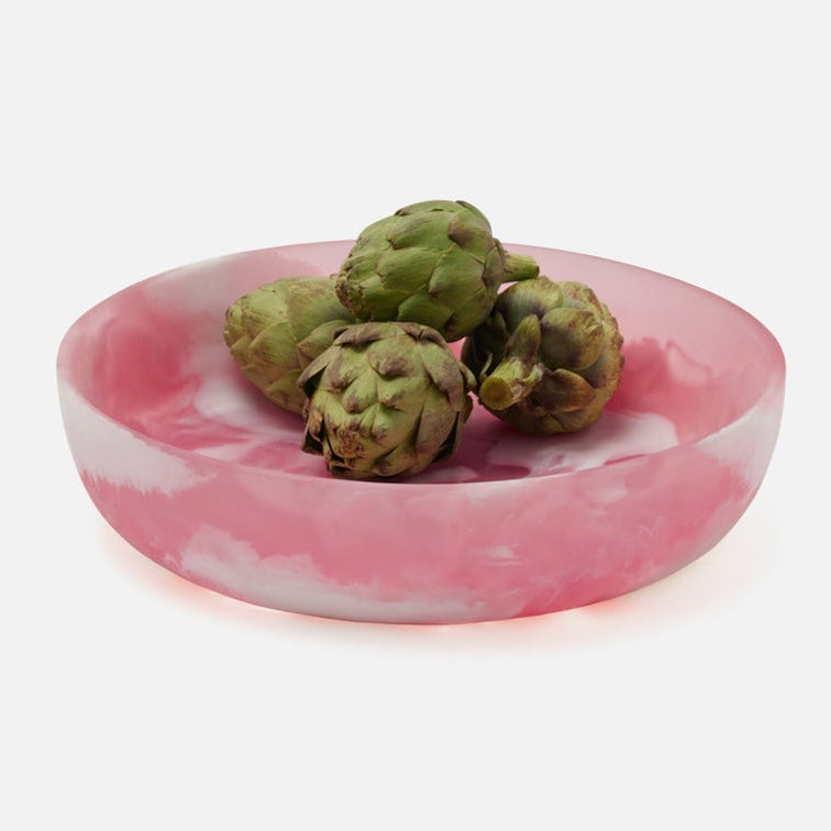 Pink and white marbled resin bowl with green artichokes on a white background