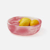 Pink resin bowl with lemons on a white background