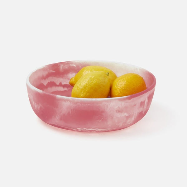 Pink resin bowl with lemons on a white background