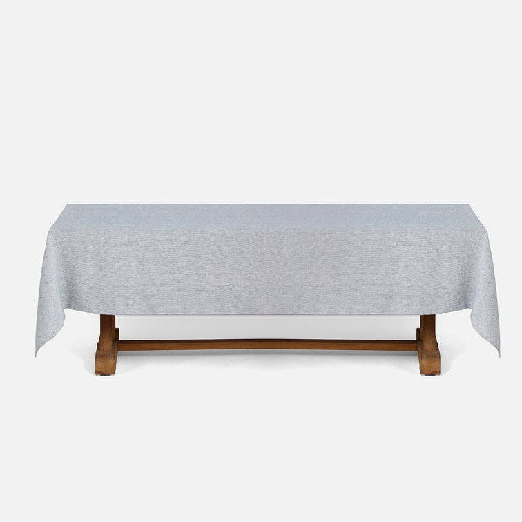 A light gray tablecloth draped over a wooden table, shown against a plain light gray background.