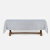 A light gray tablecloth draped over a wooden table, shown against a plain light gray background.