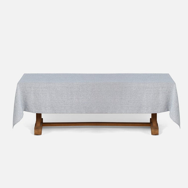 A light gray tablecloth draped over a wooden table, shown against a plain light gray background.