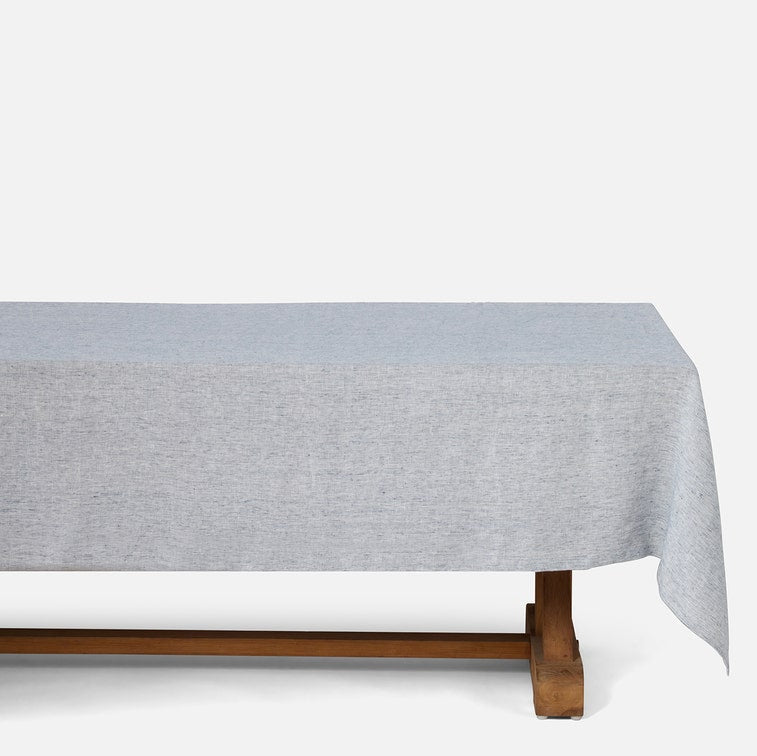 A light gray heathered tablecloth draped over a wooden bench, shown against a plain white studio background.