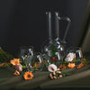Set of glass tumblers and a carafe on a dark surface with floral decorations.