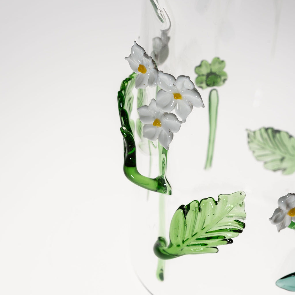 Clear glass pitcher with floral design on a white background