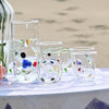 Collection of glass art pieces including vases and a fish-shaped object on a white surface with a blurred natural background.