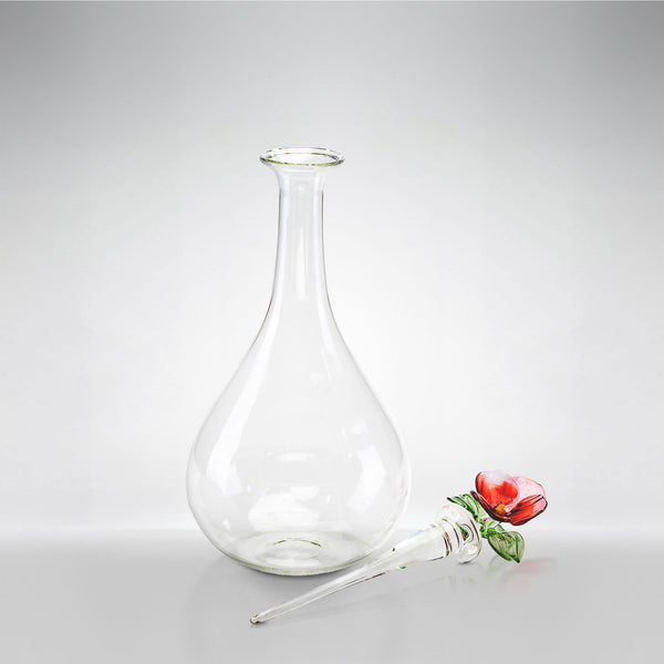 Clear glass carafe with a decorative pansy on a light gray background