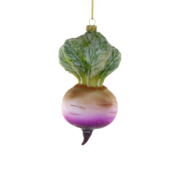 A decorative glass ornament shaped like a turnip, featuring green leafy top, a beige and white bulbous body, a purple gradient section, and a small dark tip, hanging from a gold string against a plain white background.