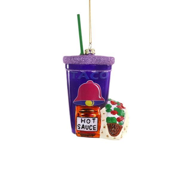 A novelty Christmas ornament shaped like a purple taco cup with a green straw, featuring a hot sauce bottle and a taco decoration attached in front, shown on a plain white background.