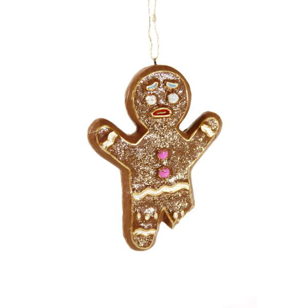 A gingerbread man Christmas ornament decorated with gold glitter, white icing details, and pink icing buttons, hanging by a thin string against a plain white background.