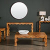Wooden coffee table with a decorative bowl, round mirror, and lamp against a dark wall.