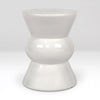 A glossy white ceramic stool with a tiered, hourglass-like design, photographed against a seamless light gray studio background.