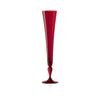 A tall, slender red glass champagne flute with a flared rim and a turned pedestal base, shown on a clean white background.