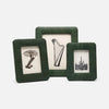 Three square dark green picture frames with a textured fabric-like finish, arranged together on a light gray background. The center frame is taller and holds a black-and-white drawing of a harp, while the side frames hold black-and-white drawings of a palm tree and a cactus.