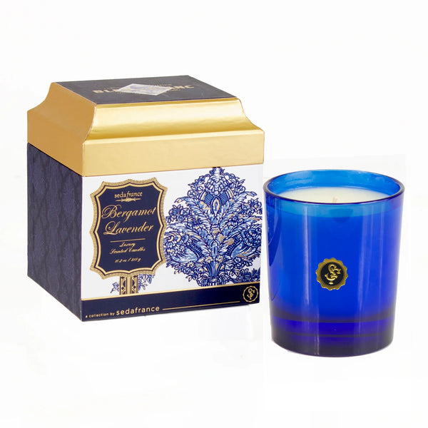 A blue glass jar candle with a gold seal is shown next to its branded packaging box, which features a blue and white floral pattern and gold accents. The brand 'Sedafrance' is visible on the box.