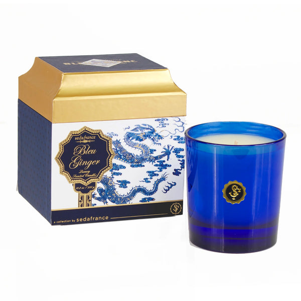A blue glass jar candle next to its branded packaging box. The box is navy blue and gold with a white porcelain-style dragon illustration.
