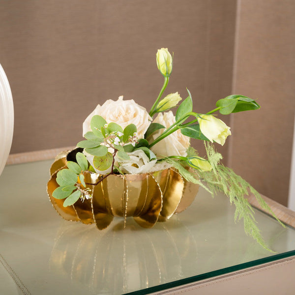 Decorative flower arrangement in a gold bowl on a glass table